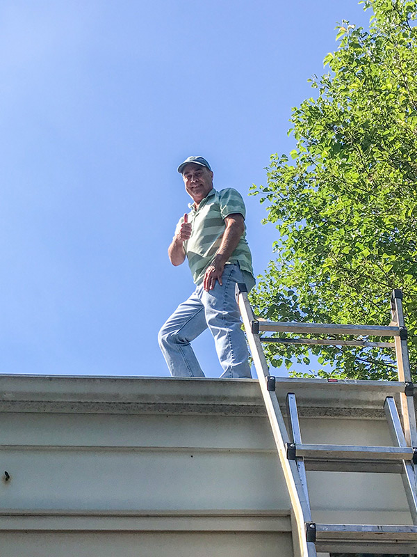 home inspector on top of house for roof inspection clarkston mi