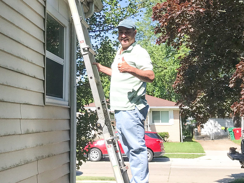 inspector climbing ladder at house exteriors for inspection clarkston mi